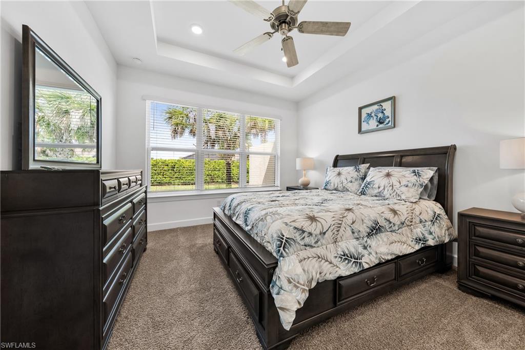 Spacious room featuring a tray ceiling with a ceiling fan, recessed lighting, and expansive windows