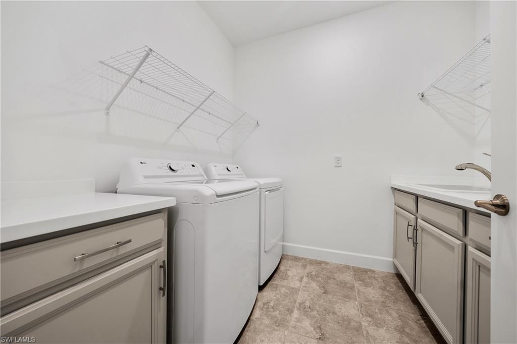 Dedicated laundry area featuring a utility sink, light gray cabinetry with brushed nickel hardware, and light-toned countertop surfaces