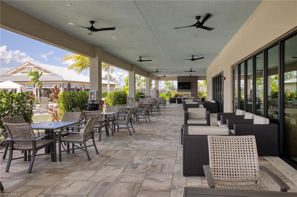 Expansive covered outdoor patio featuring a neutral-toned paver floor, multiple ceiling fans, and recessed lighting
