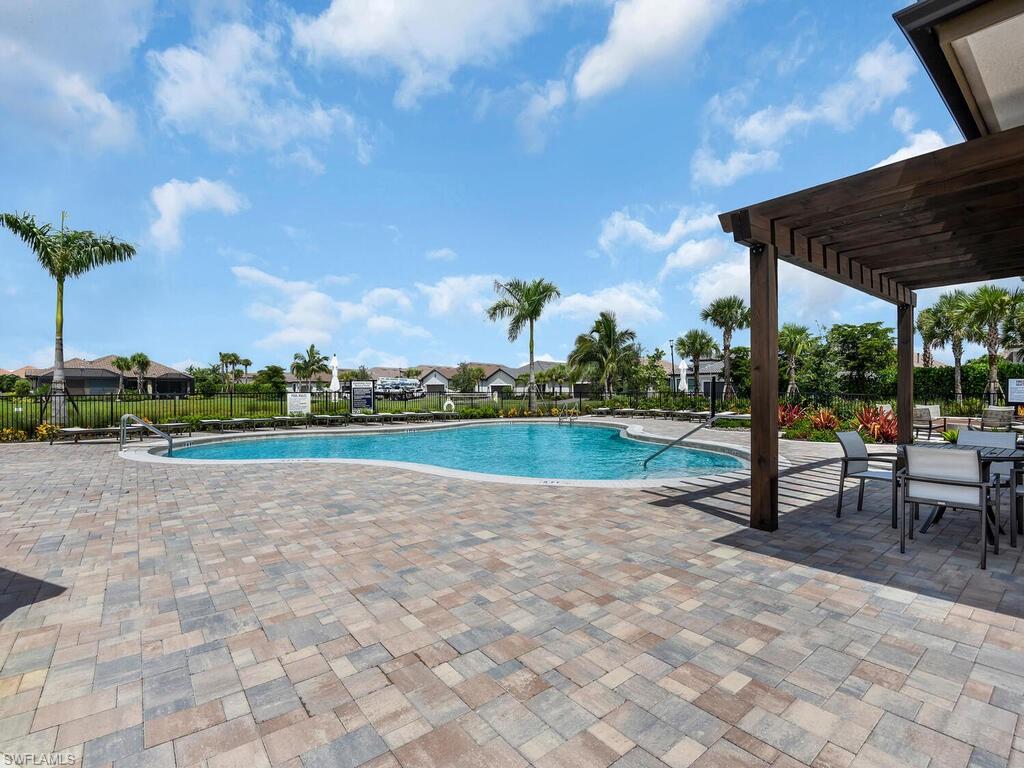 Neighborhood Curved swimming pool bordered by a multi-toned paver patio