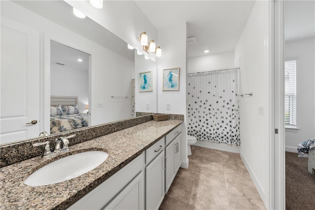 Bathroom vanity featuring an integrated sink, polished chrome faucet, and a granite-style countertop