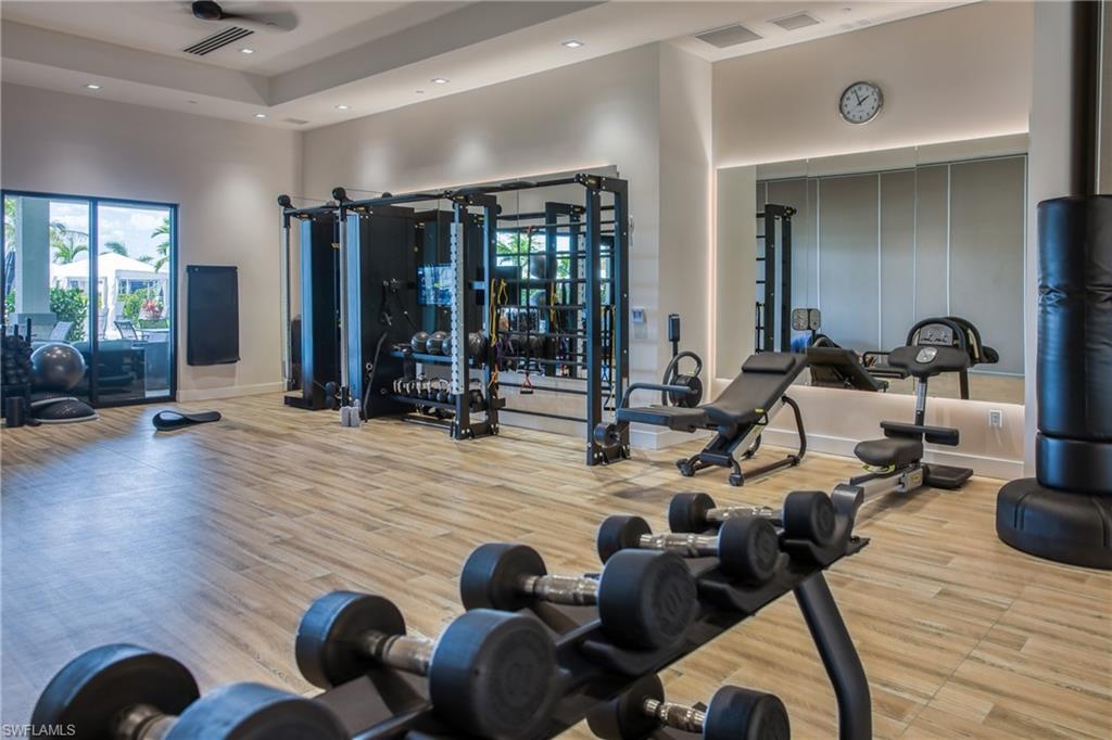 Dedicated fitness space featuring wood-finish flooring, recessed lighting, and a full-wall mirror