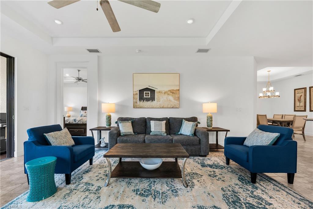 Open-concept living space featuring a tray ceiling with a ceiling fan and recessed lighting