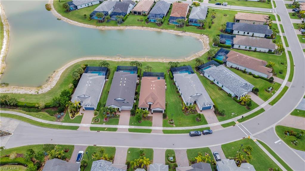 Aerial perspective showcasing residential properties with a curved street, manicured lawns, and a prominent water feature