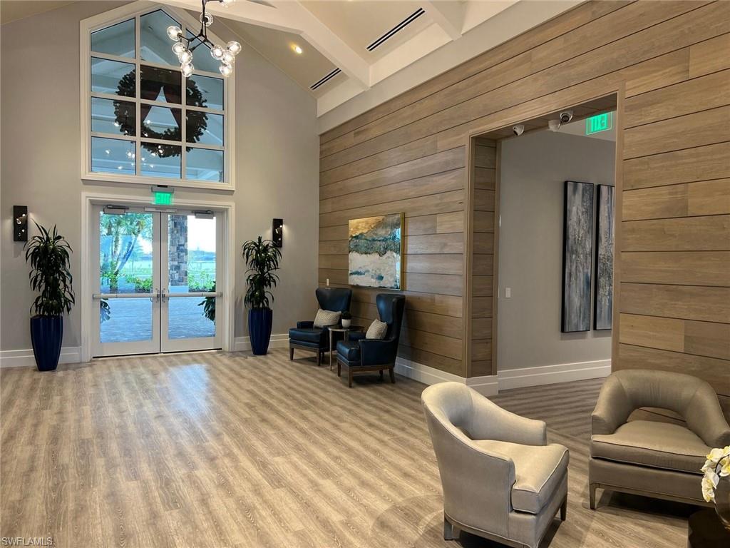 Spacious interior featuring soaring vaulted ceilings, a large arched window with transom detailing, and wood-finish flooring
