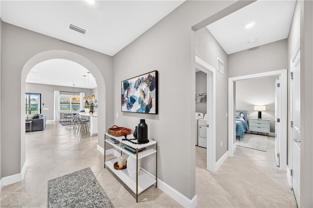 Foyer featuring large format tile flooring, arched entryway, recessed lighting, and white baseboards