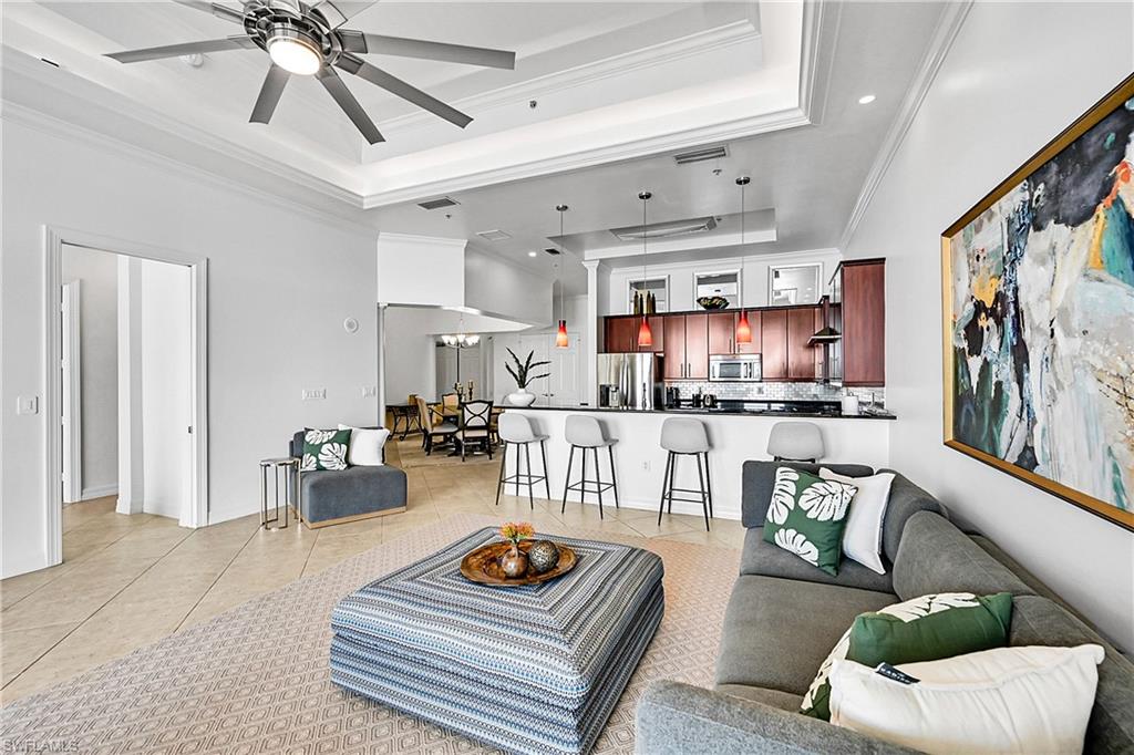 Living room featuring a tray ceiling, light tile patterned floors, ornamental molding, a ceiling fan, and recessed lighting