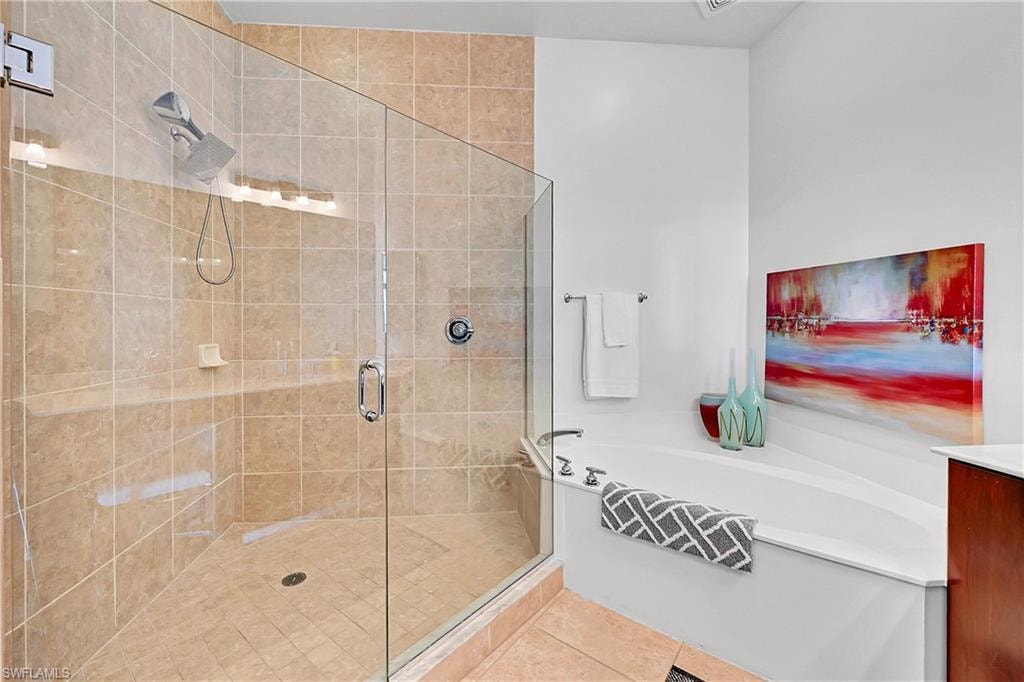 Bathroom with a stall shower, tile patterned flooring, and a bath