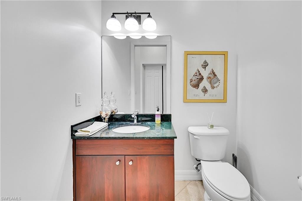 Bathroom featuring baseboards, toilet, vanity, and tile patterned floors