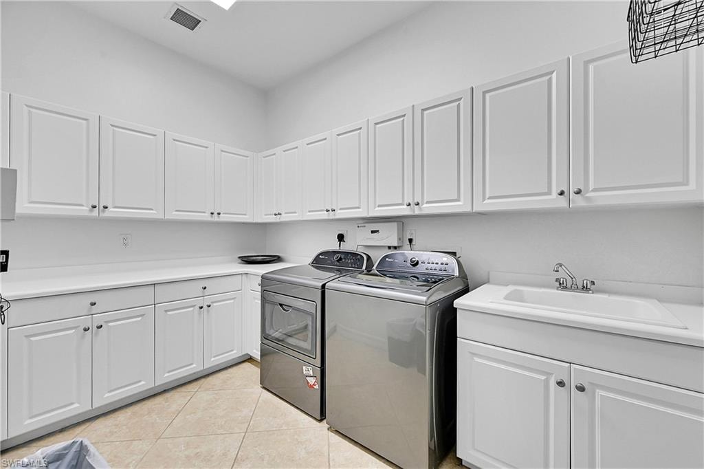 Laundry area featuring washer and dryer, cabinet space, and light tile patterned flooring