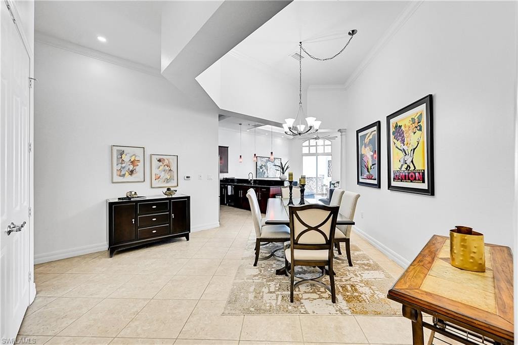 Dining area with ornamental molding, a chandelier, light tile patterned floors, and baseboards