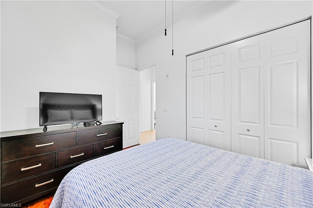 Bedroom featuring crown molding, a closet, and light wood-style floors