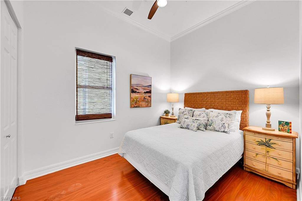 Bedroom with ornamental molding, wood finished floors, a closet, baseboards, and a ceiling fan