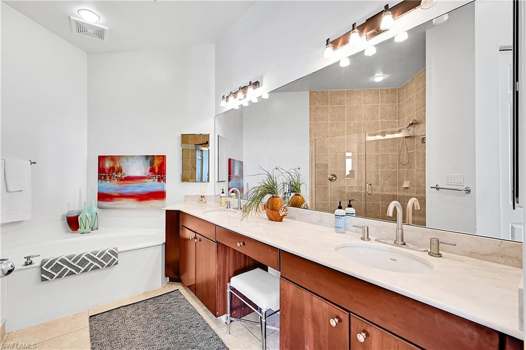 Full bath featuring a stall shower, double vanity, tile patterned floors, and a bath