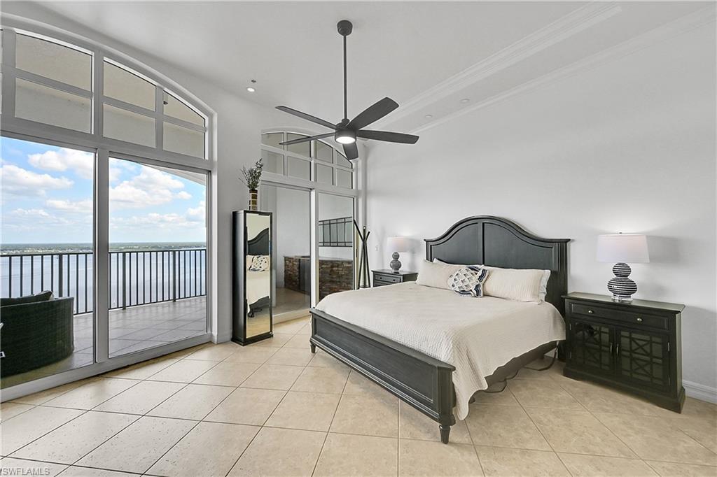 Bedroom featuring a water view, access to exterior, light tile patterned flooring, baseboards, and crown molding