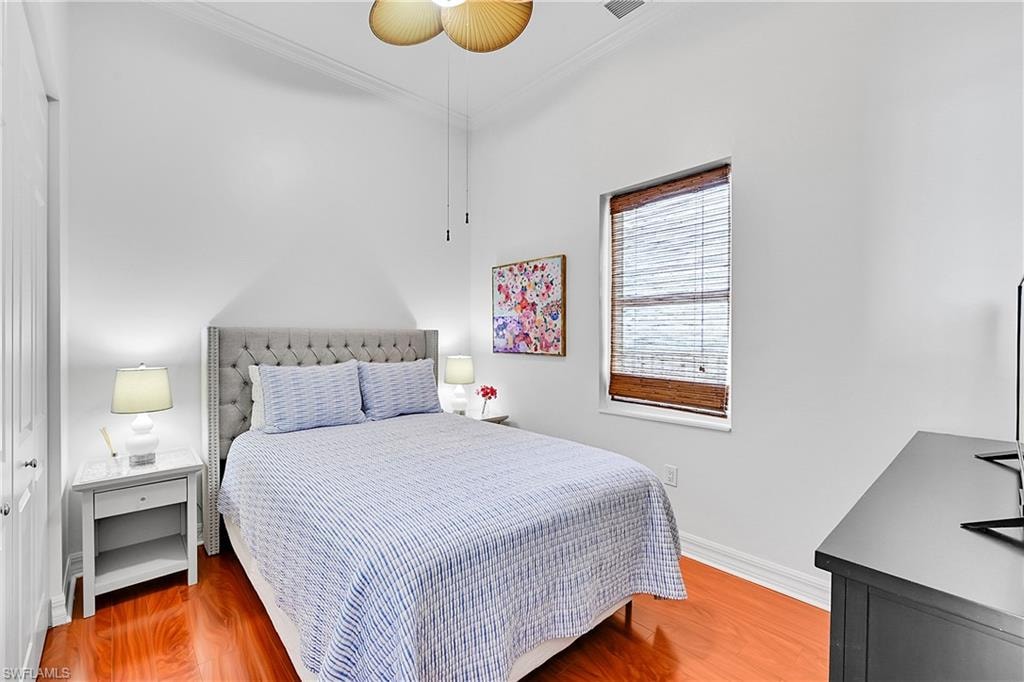 Bedroom featuring crown molding, wood finished floors, baseboards, and ceiling fan