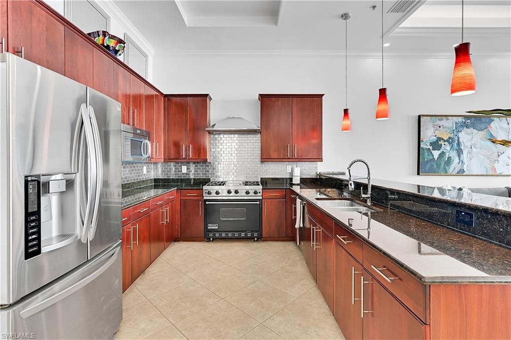 Kitchen featuring stainless steel appliances, a peninsula, a sink, a tray ceiling, and light tile patterned floors