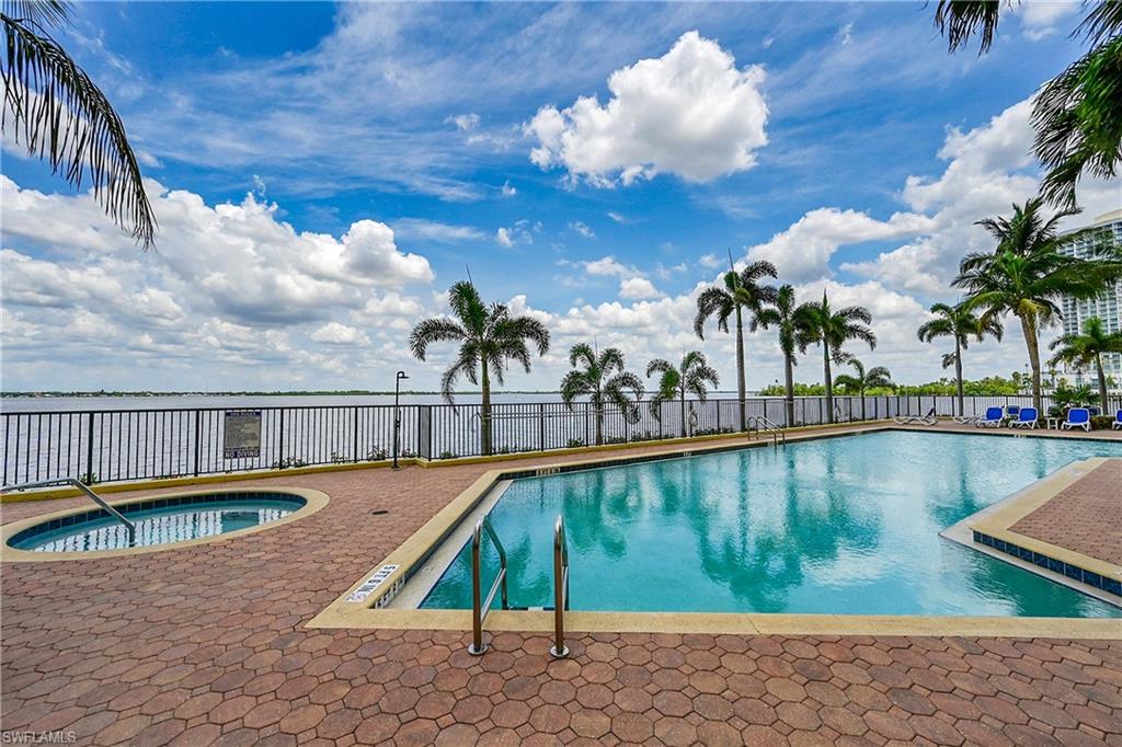 Community pool featuring a hot tub, fence, and a patio