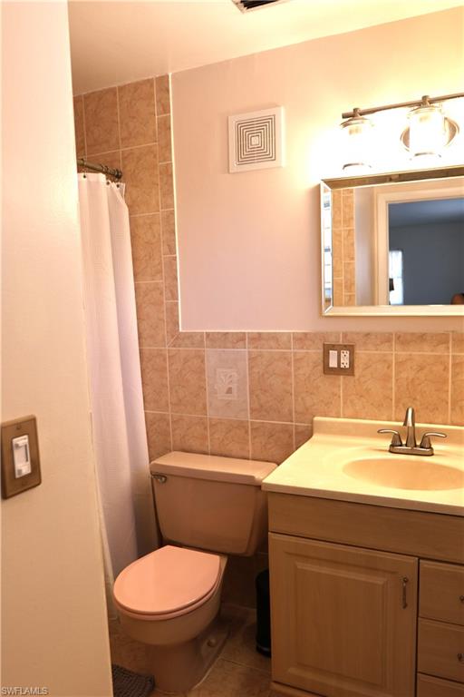Bathroom featuring a neutral-toned vanity with an integrated sink, a rectangular mirror, and a tiled shower surround