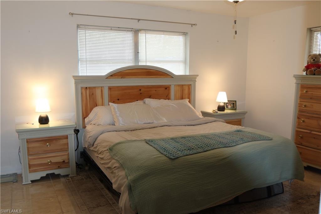 Bedroom featuring a window with horizontal blinds, a ceiling fan, and tile flooring