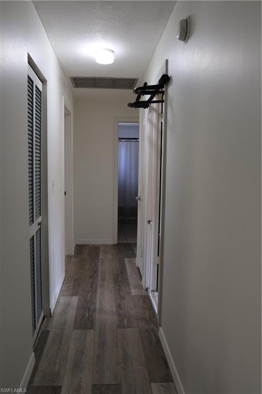 Hallway featuring wood-finish flooring, white painted walls, and ceiling-mounted lighting