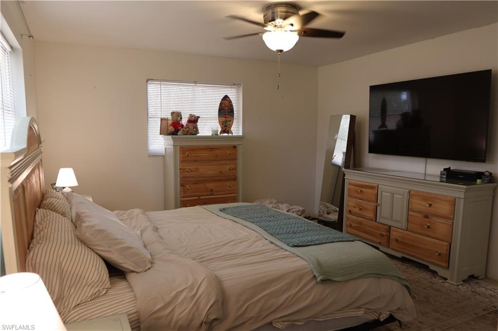 Bedroom featuring overhead ceiling fan with integrated lighting, multiple windows with blinds, and light-toned walls
