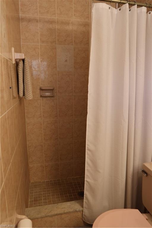 Enclosed shower with full-height beige tile surround, mosaic tile flooring, and integrated soap dish