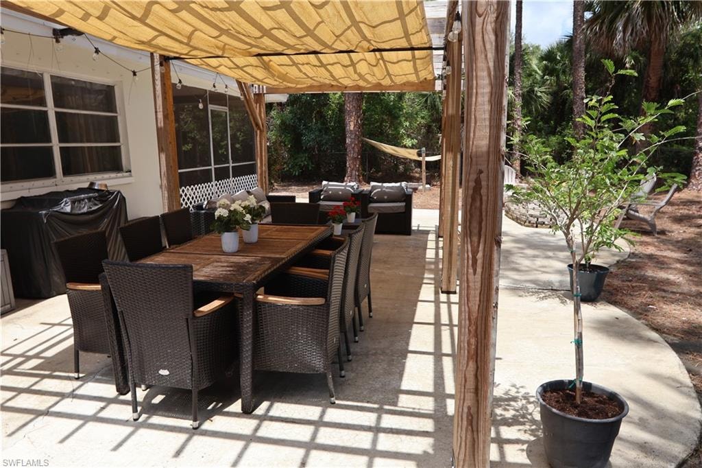 Expansive concrete patio featuring a shade canopy, wood pergola, and string lighting