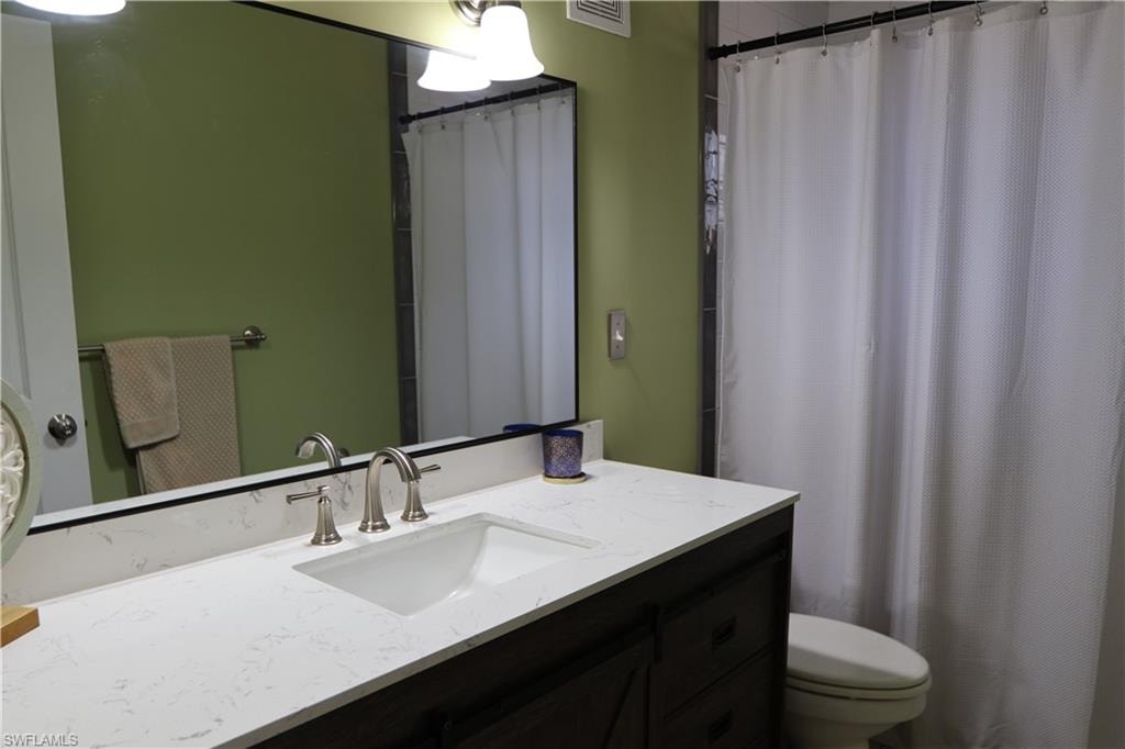 Bathroom featuring a dark wood-finish vanity with an undermount sink, a light-toned countertop, and brushed nickel fixtures