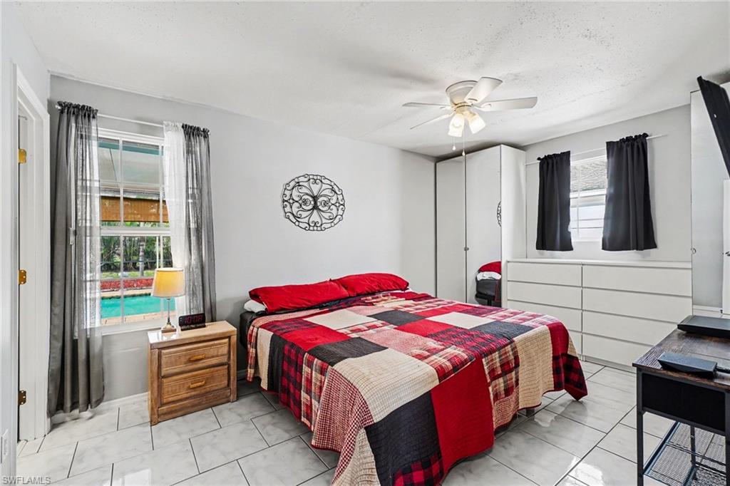 Bedroom featuring tiled flooring, a ceiling fan with integrated lighting, and two windows