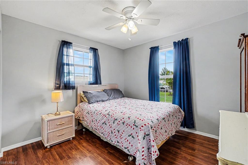 Spacious room featuring wood-finish flooring, two window openings, and a ceiling fan with integrated lighting