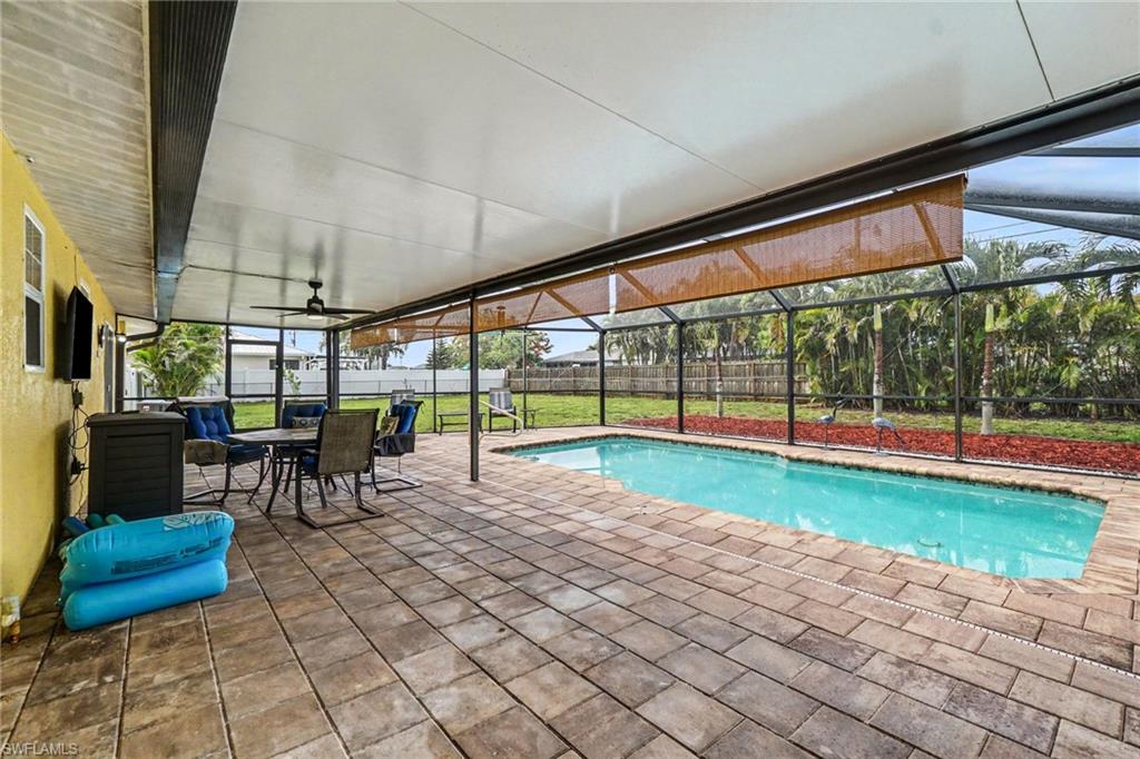 Screened patio featuring a paved deck, in-ground swimming pool, and an outdoor ceiling fan