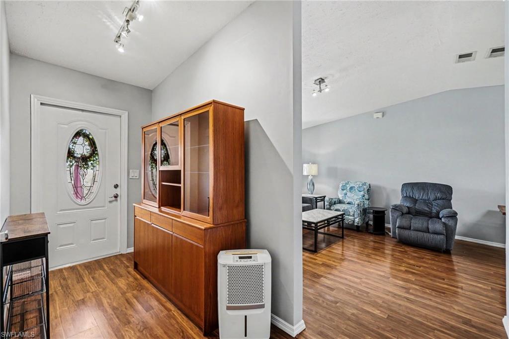 Entryway featuring wood-finish flooring, a white door with an oval decorative glass insert, and track lighting