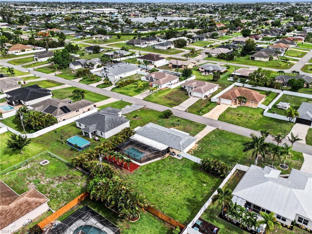 Aerial perspective of a residential neighborhood featuring single-story homes with shingle and metal roofs, some with screen-enclosed pools