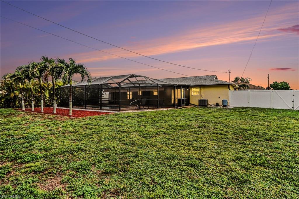 Expansive grassy lawn with a screened-in pool area featuring a paved deck and integrated steps