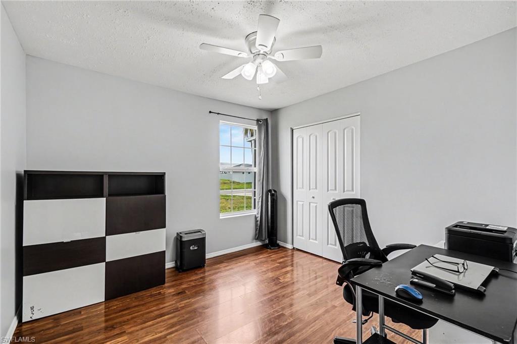 Room with wood-finish flooring, a ceiling fan, and a window offering exterior scenery