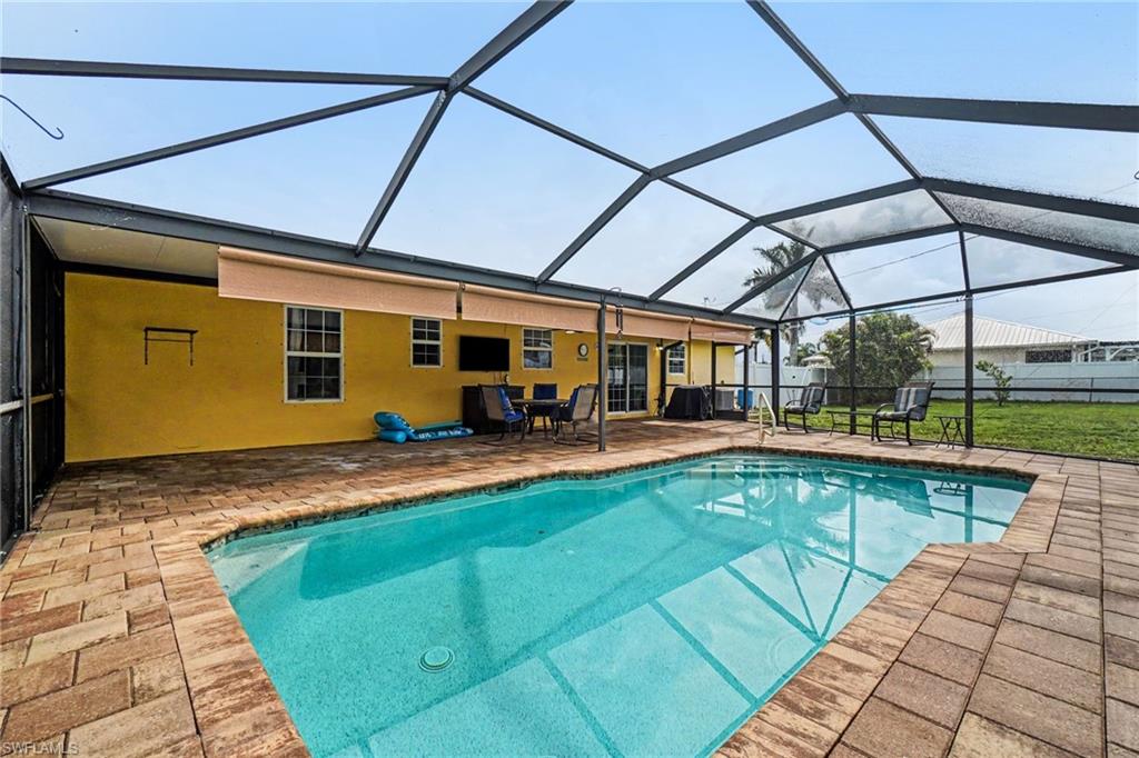 Screened-in swimming pool enclosure featuring a rectangular pool, brick paver decking, and a covered lanai