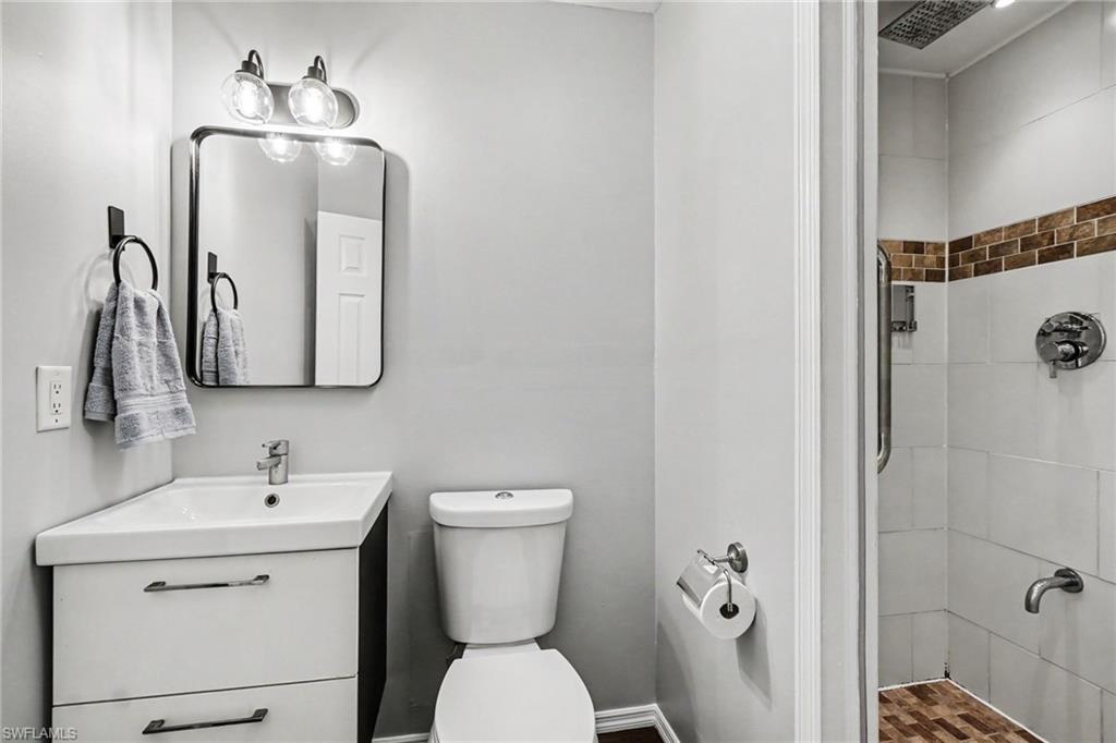 Bathroom featuring a white vanity with integrated sink, rectangular mirror with rounded corners, and a contemporary vanity light fixture