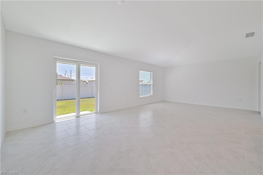 Unfurnished room featuring vaulted ceiling and light tile patterned floors
