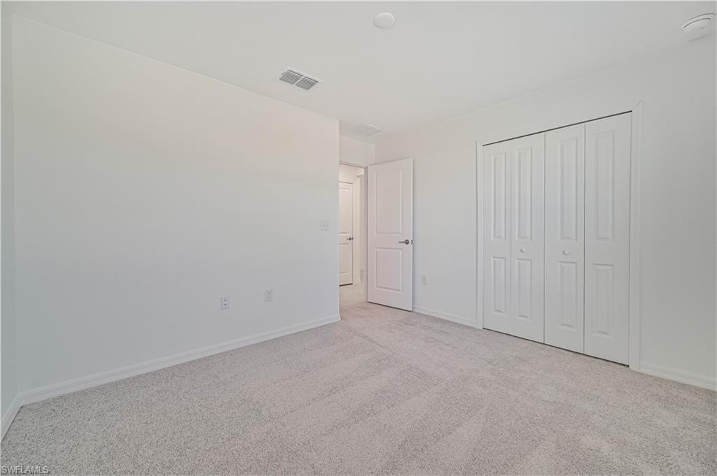 Unfurnished bedroom featuring light colored carpet and a closet