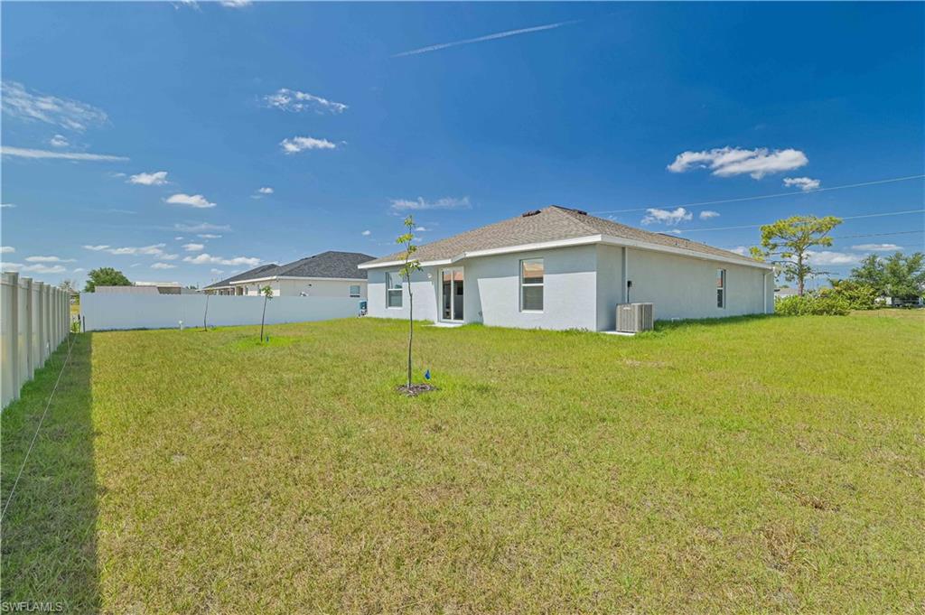 Back of property with a yard and central air condition unit