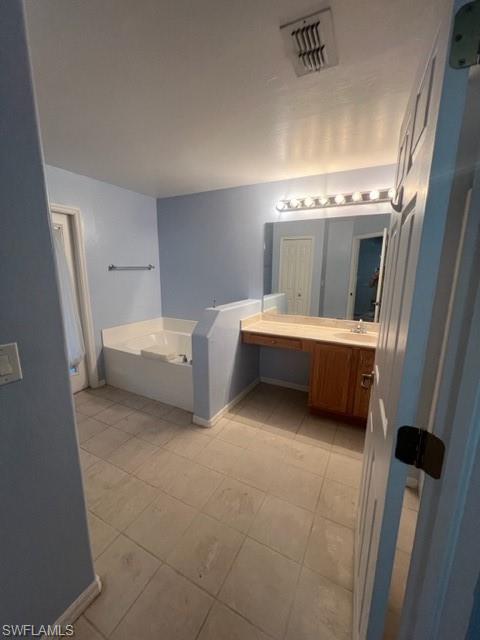 Bathroom with a bathing tub, tile patterned flooring, and vanity