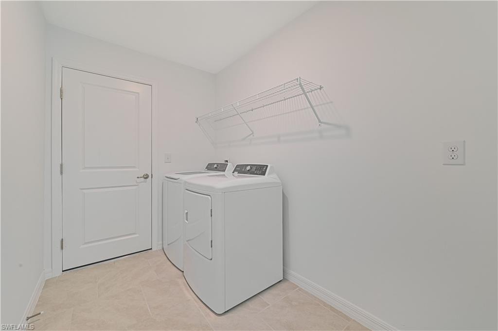 Laundry area featuring light tile patterned floors and washing machine and dryer