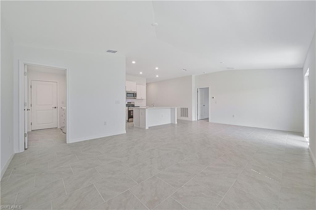 Unfurnished living room featuring vaulted ceiling