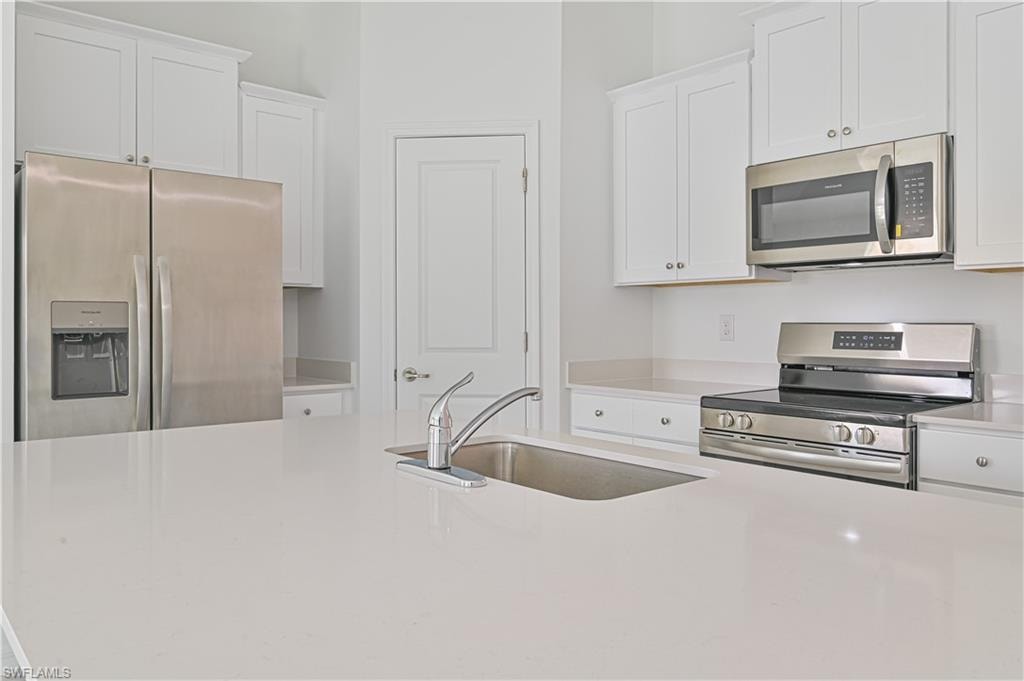 Kitchen featuring white cabinets, stainless steel appliances, and sink