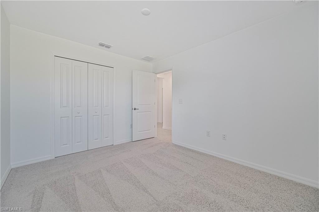 Unfurnished bedroom featuring light carpet and a closet