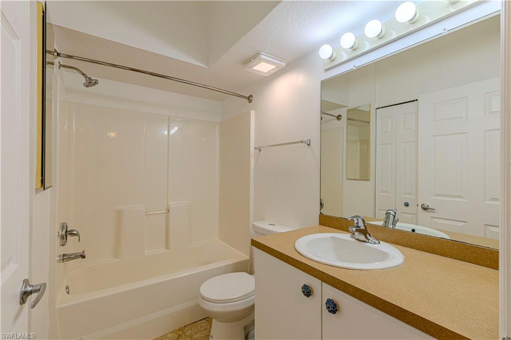 Bathroom featuring a tub/shower combination with a curved shower rod, vanity with an integrated sink, broad wall mirror, and overhead vanity lighting