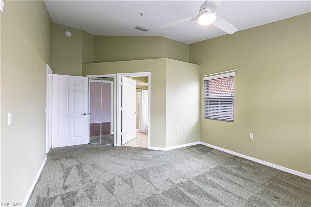 Primary Bedroom with a ceiling fan, window with blinds, and white paneled doors leading to another room and an en-suite bathroom