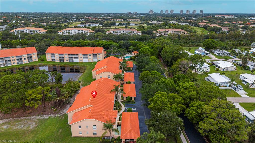 Aerial perspective showcasing multiple residential buildings with terracotta-style tile roofs, surrounded by dense green foliage