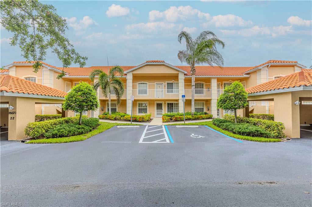 Two-story condominium building featuring a terracotta tile roof and light-colored stucco exterior